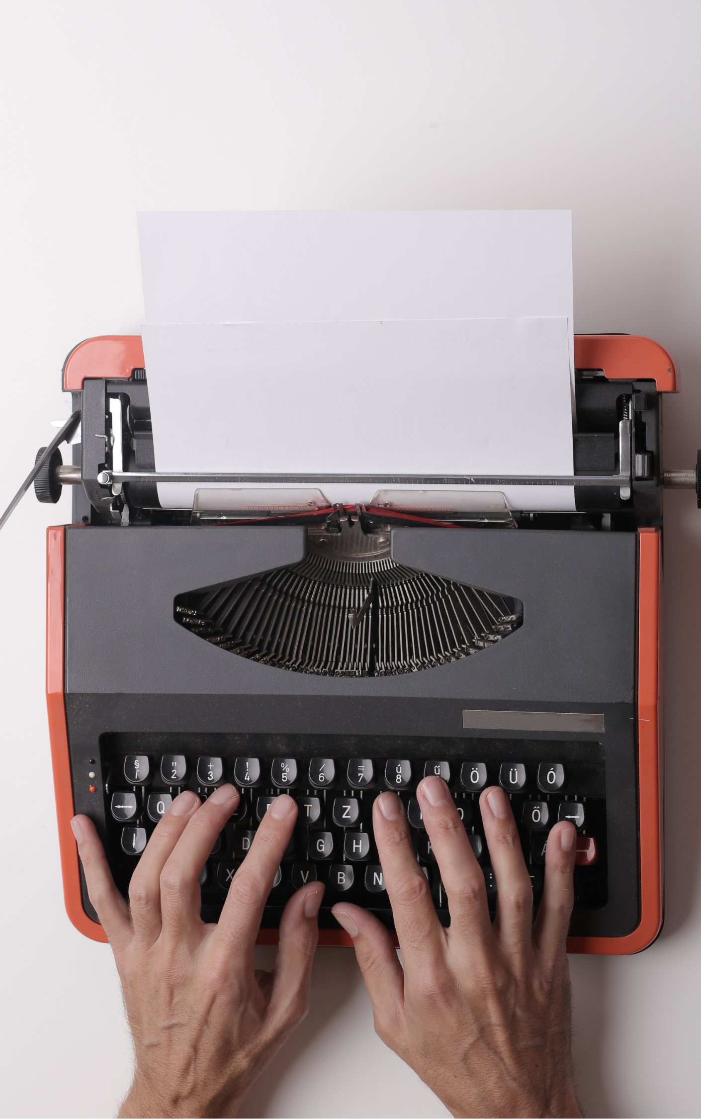 dos manos sobre una máquina de escribir de color rojo y negro